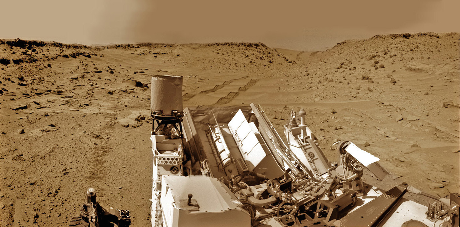 Curiosity looks back eastward to ‘Dingo Gap’ sand dune inside Gale Crater. After crossing over the dune on Feb. 9, 2014 the rover drove into the ‘Moonlight Valley’. The parallel rover wheel tracks are 9 feet (2.7 meters) apart. Image: NASA/JPL/Ken Kremer/Marco Di Lorenzo