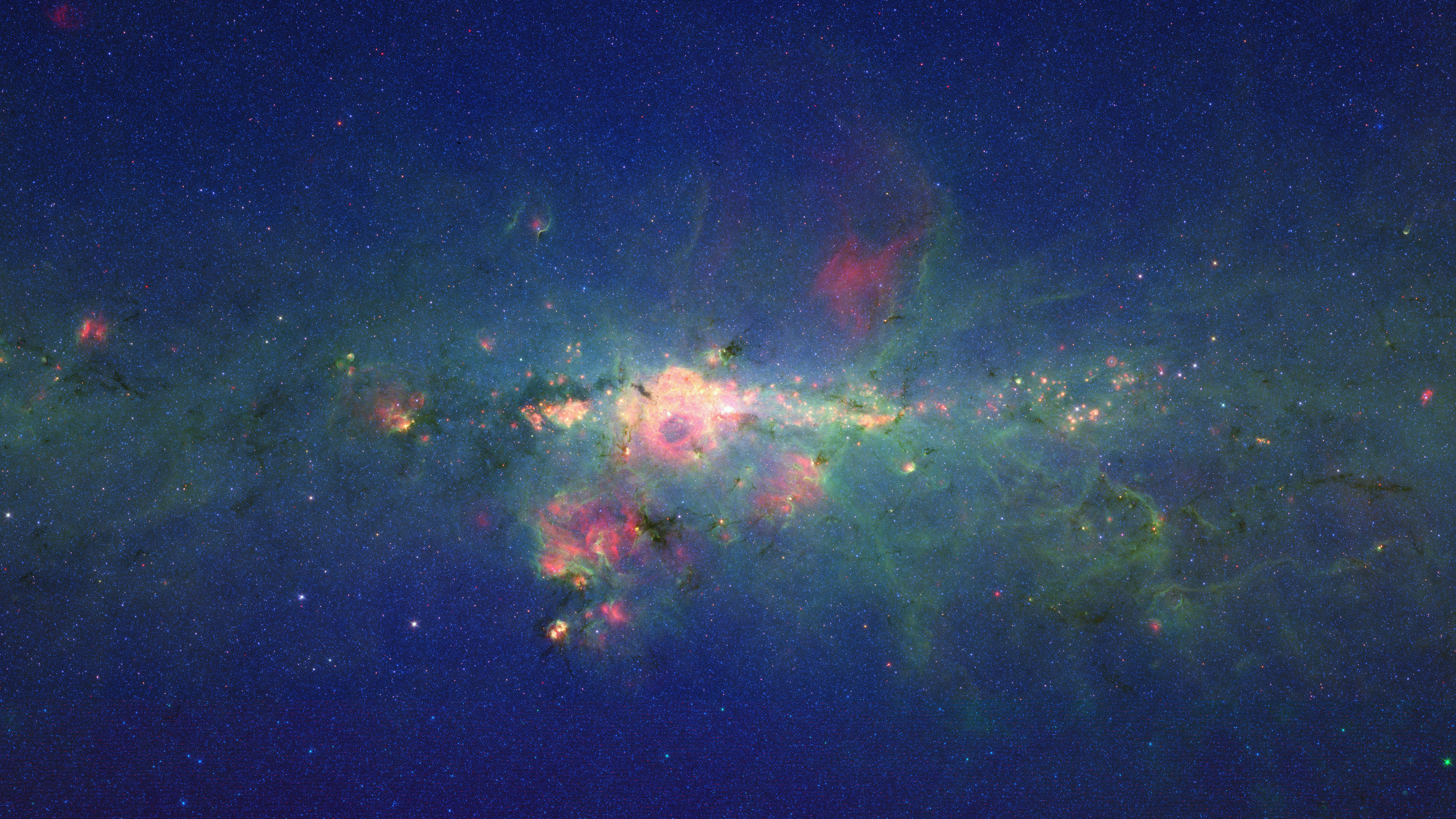 Stars Gather in ‘Downtown’ Milky Way: The region around the center of our Milky Way galaxy glows colorfully in this new version of an image taken by the Spitzer Space Telescope. The image is displayed (left picture) on a quarter-of-a-billion-pixel, high-definition 23-foot-wide (7-meter) LCD science visualization screen at NASA’s Ames Research Center in Moffett Field, Calif. Credit: NASA/Ames/JPL-Caltech
