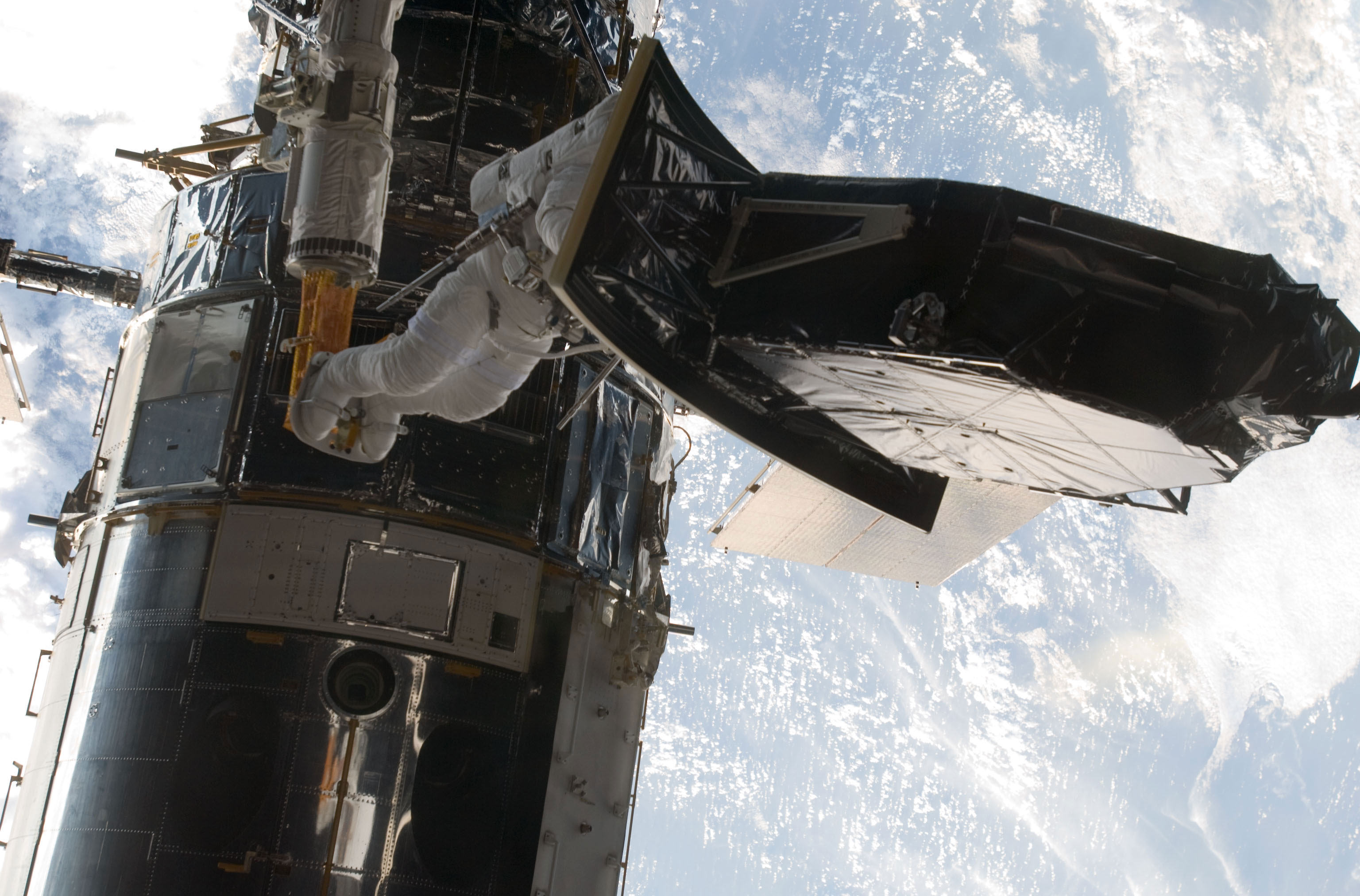 Image #5: But for the absence of gravity, astronaut Andrew Feustel, perched on the end of the remote manipulator system arm, would be a bit top heavy as he helps to install the Wide Field Camera 3 (WFC3) during a May 2009 spacewalk to upgrade the Hubble Space Telescope. Out of frame is veteran astronaut John Grunsfeld, his spacewalking crewmate. The pair kicked off five back to back days of extravehicular activity for the STS-125 crew. Credit: NASA