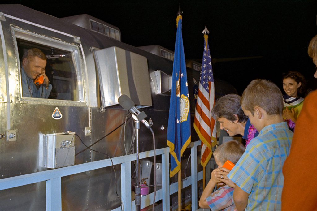 The Apollo 11 crewmen, still under a 21-day quarantine, are greeted by their family at Ellington Air Force Base after a flight aboard a C141 transport from Hawaii. 