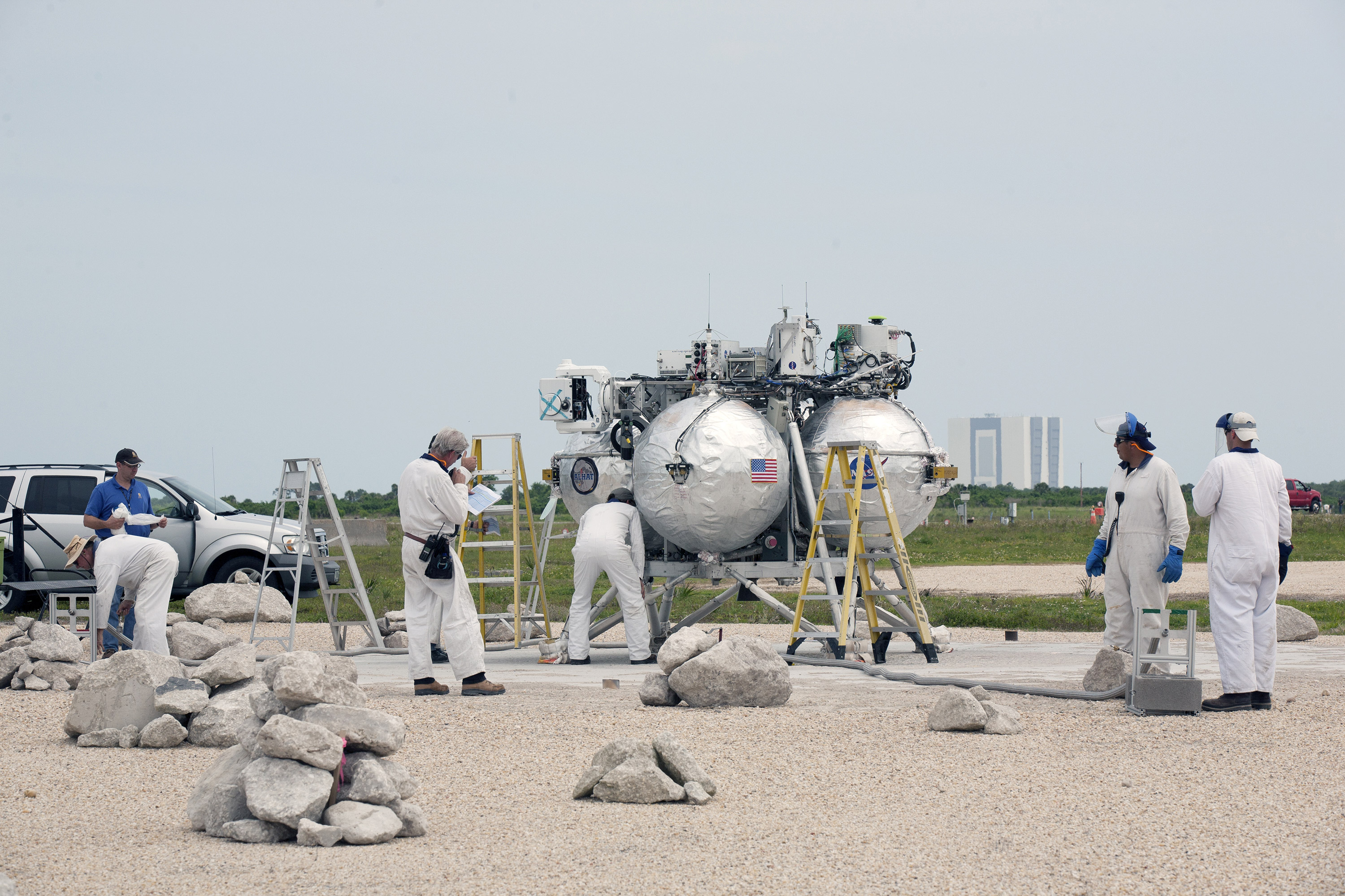 Engineers and technicians check the Project Morpheus prototype lander after it touched down on a dedicated landing pad inside the hazard field at the Shuttle Landing Facility at Kennedy Space Center. Morpheus launched on a free-flight test from a new launch pad at the north end of the facility. Credit: NASA/Kim Shiflett