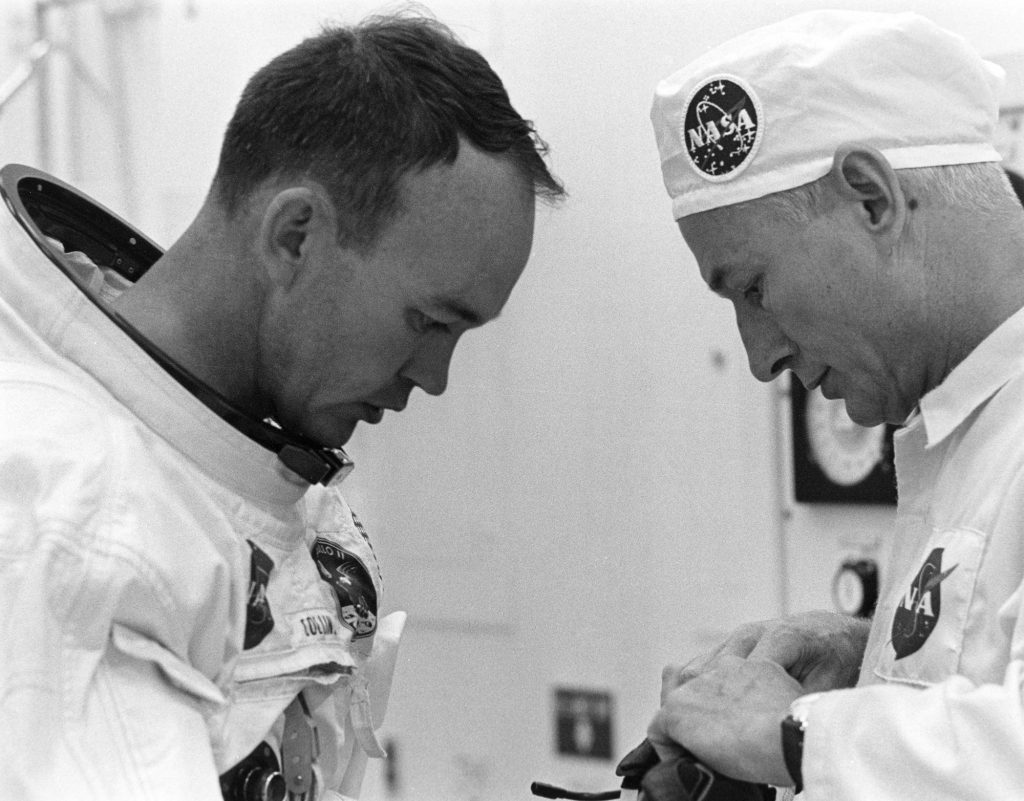 Michael Collins is helped by suit tech Joe Schmitt while suiting up on July 16, 1969.