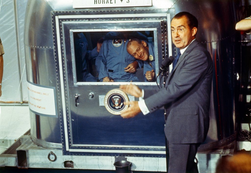 Already confined to the Mobile Quarantine Facility, President Richard Nixon welcomes the Apollo 11 astronauts aboard the U.S.S. Hornet. 