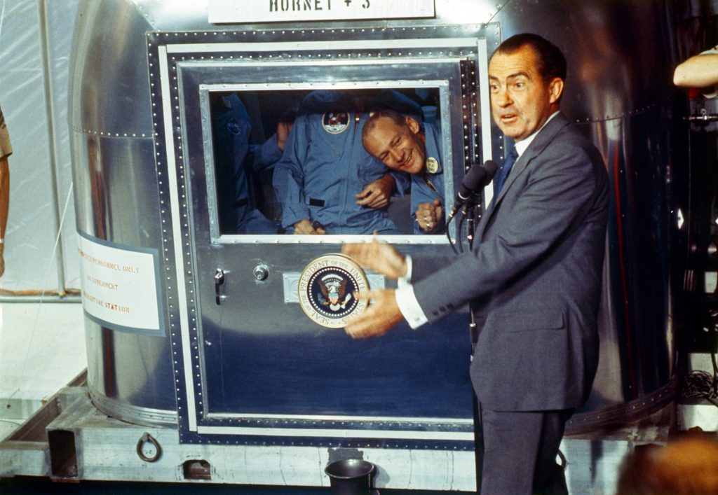 Already confined to the Mobile Quarantine Facility, President Richard Nixon welcomes the Apollo 11 astronauts aboard the U.S.S. Hornet.