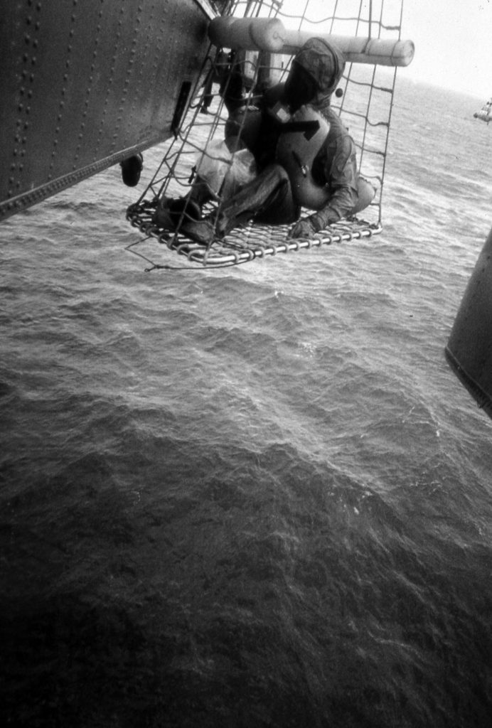 An unidentified crew member is hoisted aboard the recovery helicoptor for transport back to USS Hornet.