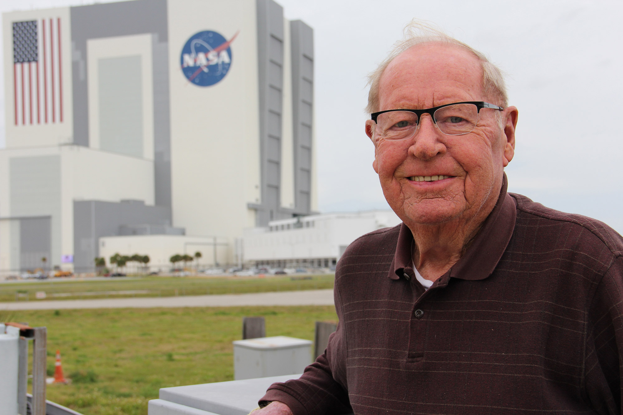 Jack King stands outside the KSC Press Center with the VAB in the background. Credit: Nicole Solomon