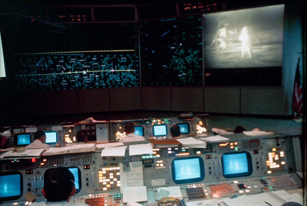 View of NASA Mission Control in Houston, Texas during the lunar surface EVA by Armstrong and Aldrin. The television monitor shows them on the surface of the moon.