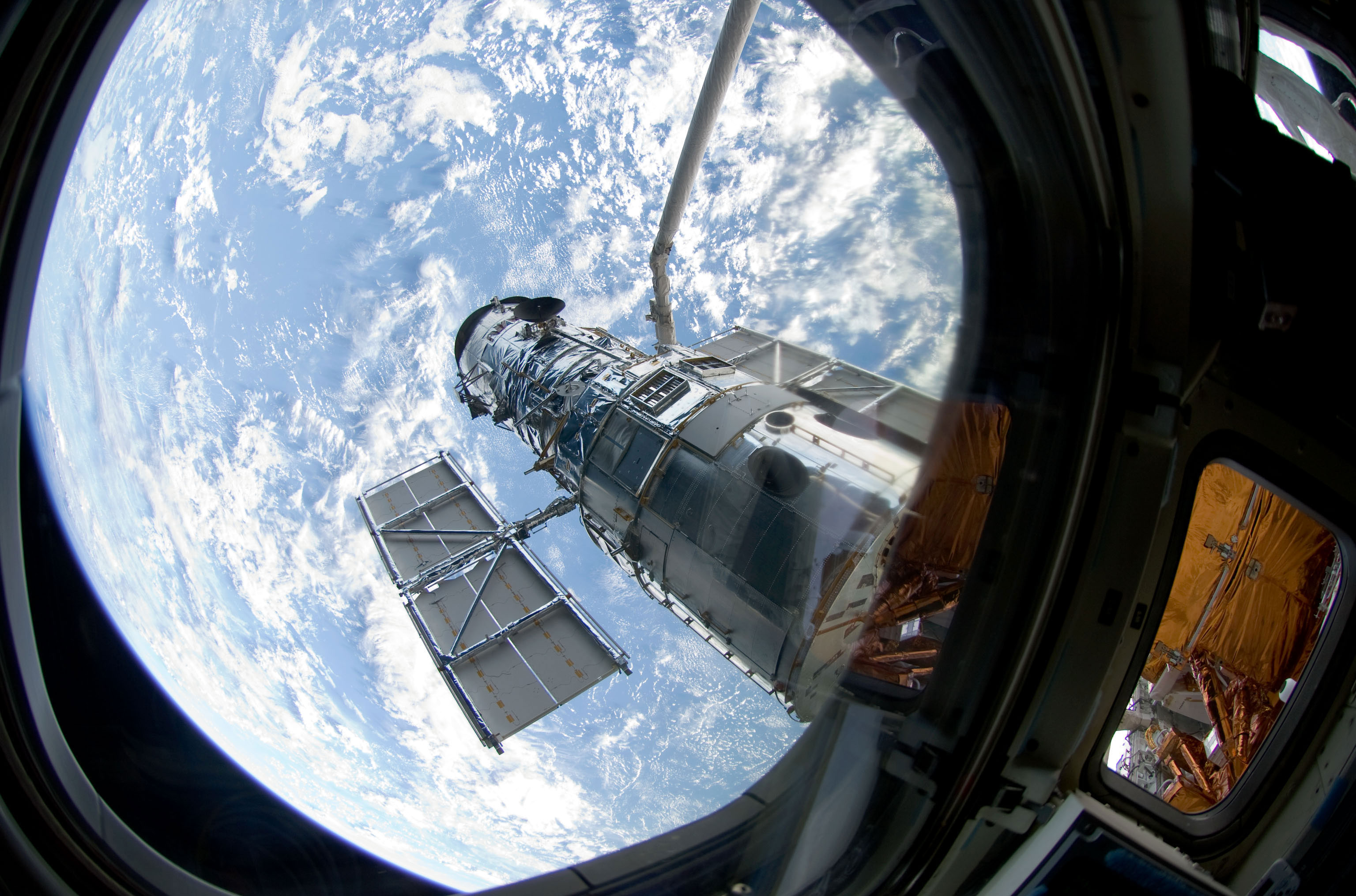 An STS-125 crewmember onboard Atlantis snapped a still photo of the Hubble Space Telescope following grapple of the giant observatory by the shuttle’s Canadian-built remote manipulator system. Credit: NASA