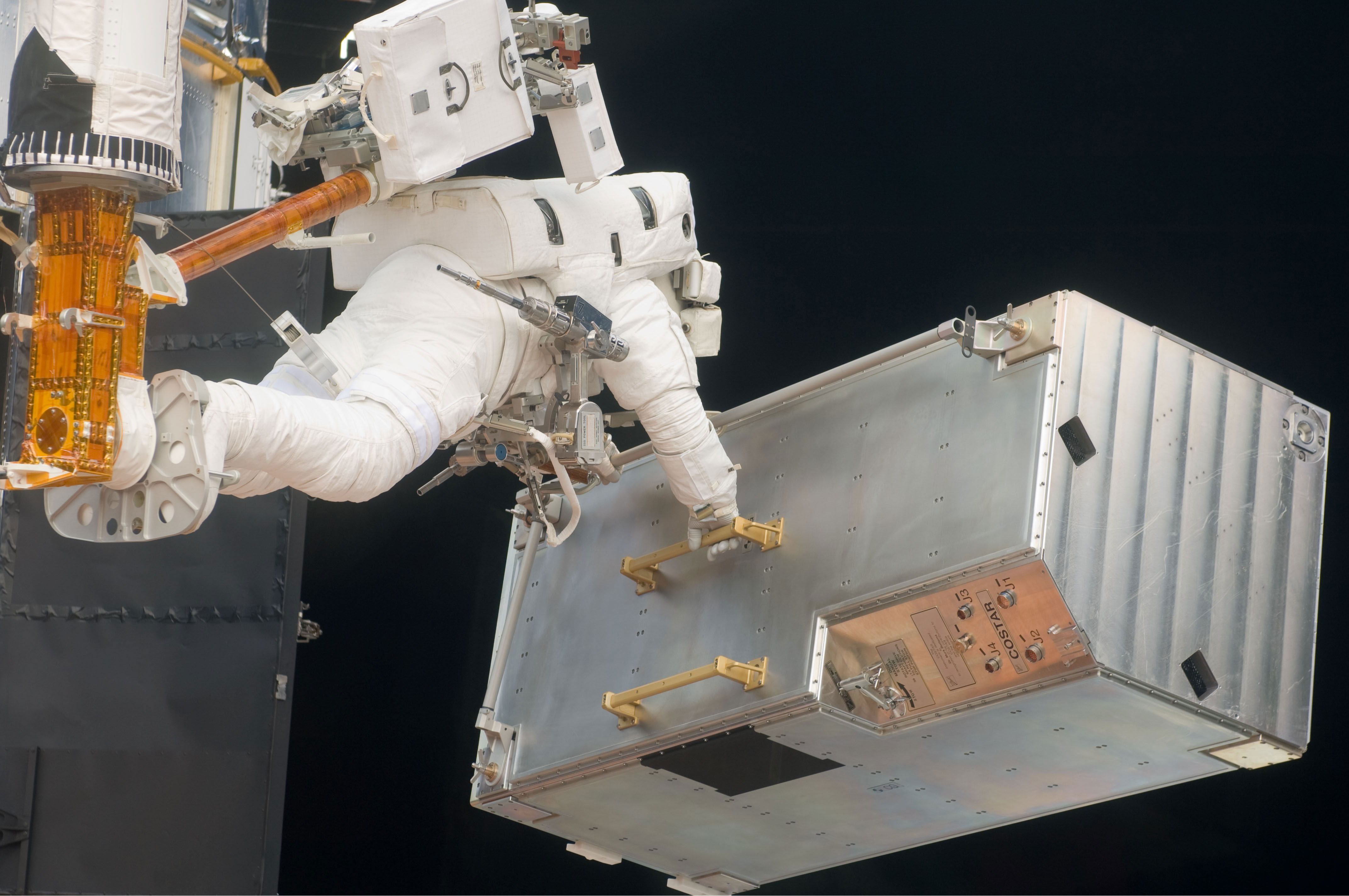 Andrew Feustel, positioned on a foot restraint on the end of Atlantis’ remote manipulator system (RMS), moves the Corrective Optics Space Telescope Axial Replacement (COSTAR) during the mission’s third EVA session to refurbish and upgrade the Hubble Space Telescope. Credit: NASA