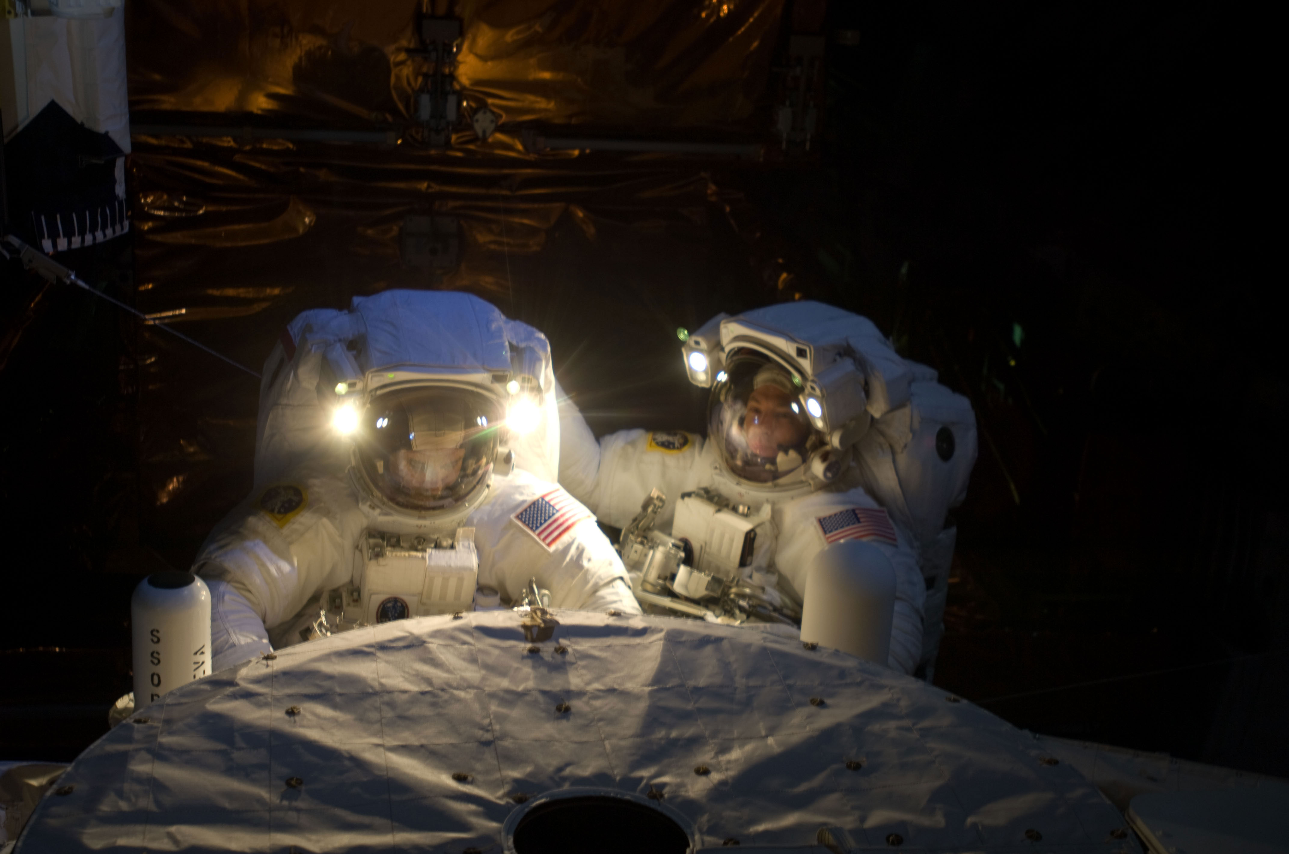 Astronauts John Grunsfeld (left) and Andrew Feustel, both STS-125 mission specialists, participate in the mission’s fifth and final ever session of extravehicular activity (EVA) to repair and upgrade the Hubble Space Telescope. During the seven-hour and two-minute spacewalk, Grunsfeld and Feustel installed a battery group replacement, removed and replaced a Fine Guidance Sensor and three thermal blankets (NOBL) protecting Hubble’s electronics. Credit: NASA