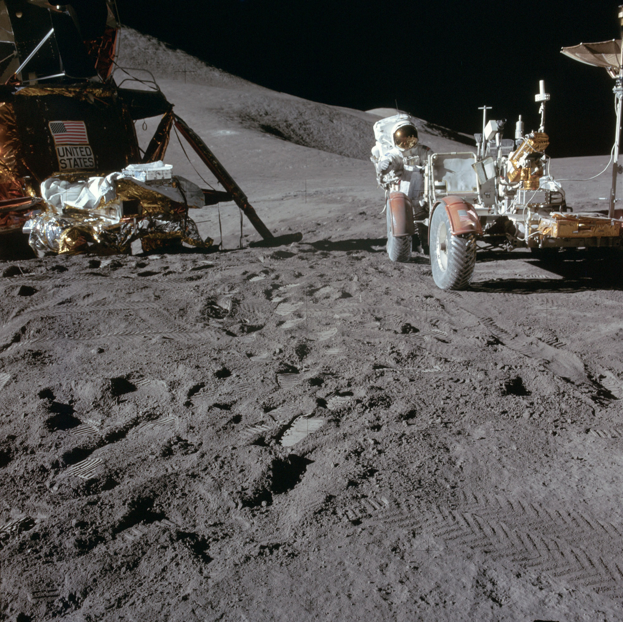Jim Irwin works at the Lunar Roving Vehicle during the first EVA at the Hadley-Apennine landing site. A portion of the Falcon Lunar Module is on the left. The undeployed Laser Ranging Retro Reflector LR-3 lies atop the LM’s Modular Equipment Stowage Assembly MESA. Credit: NASA via Retro Space Images