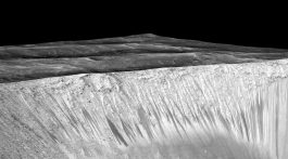 Dark narrow streaks called recurring slope lineae emanating out of the walls of Garni crater on Mars. The dark streaks here are up to few hundred meters in length. They are hypothesized to be formed by flow of briny liquid water on Mars. Credit: NASA/JPL/University of Arizona