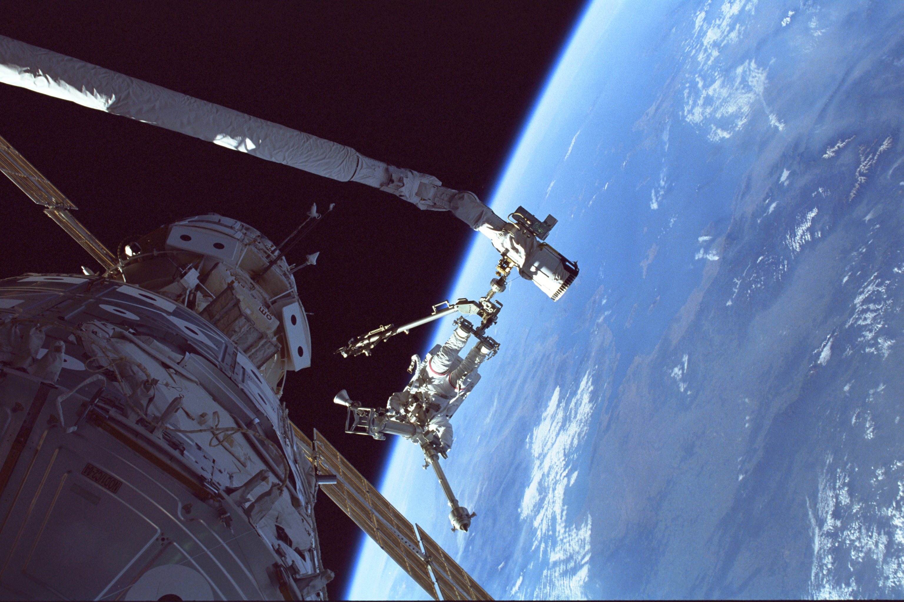 The Shuttle Discovery and the STS-96 crew made history in May 1999 when they became the first crew and orbiter to visit the International Space Station. Here, the Aegean Sea is the back drop for mission specialist Tamara E. Jernigan as she handles the American-built crane, which she later helped to install on the Station during a May 30 spacewalk. Jernigan's feet are anchored to a mobile foot restraint connected to Discovery's Canadian-built robot arm. Photo: NASA
