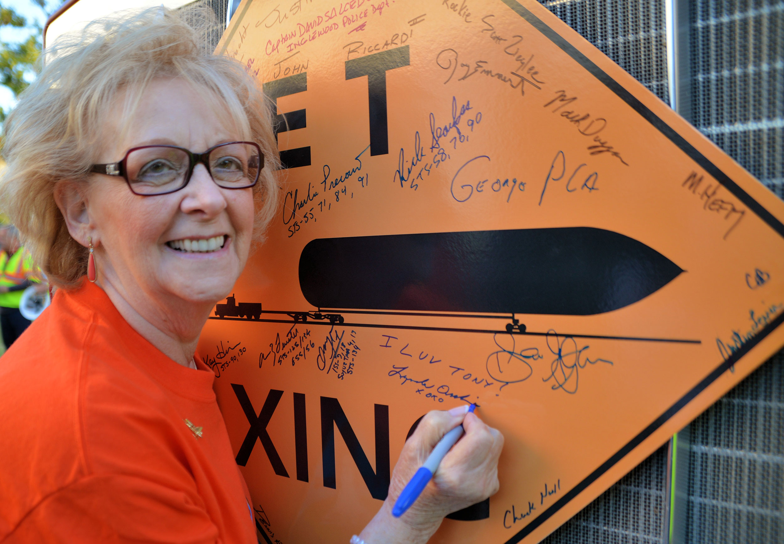 Mrs. Lynda Oschin signs an 'ET Xing' sign during the day's festivities. Credit: Julian Leek/JNN