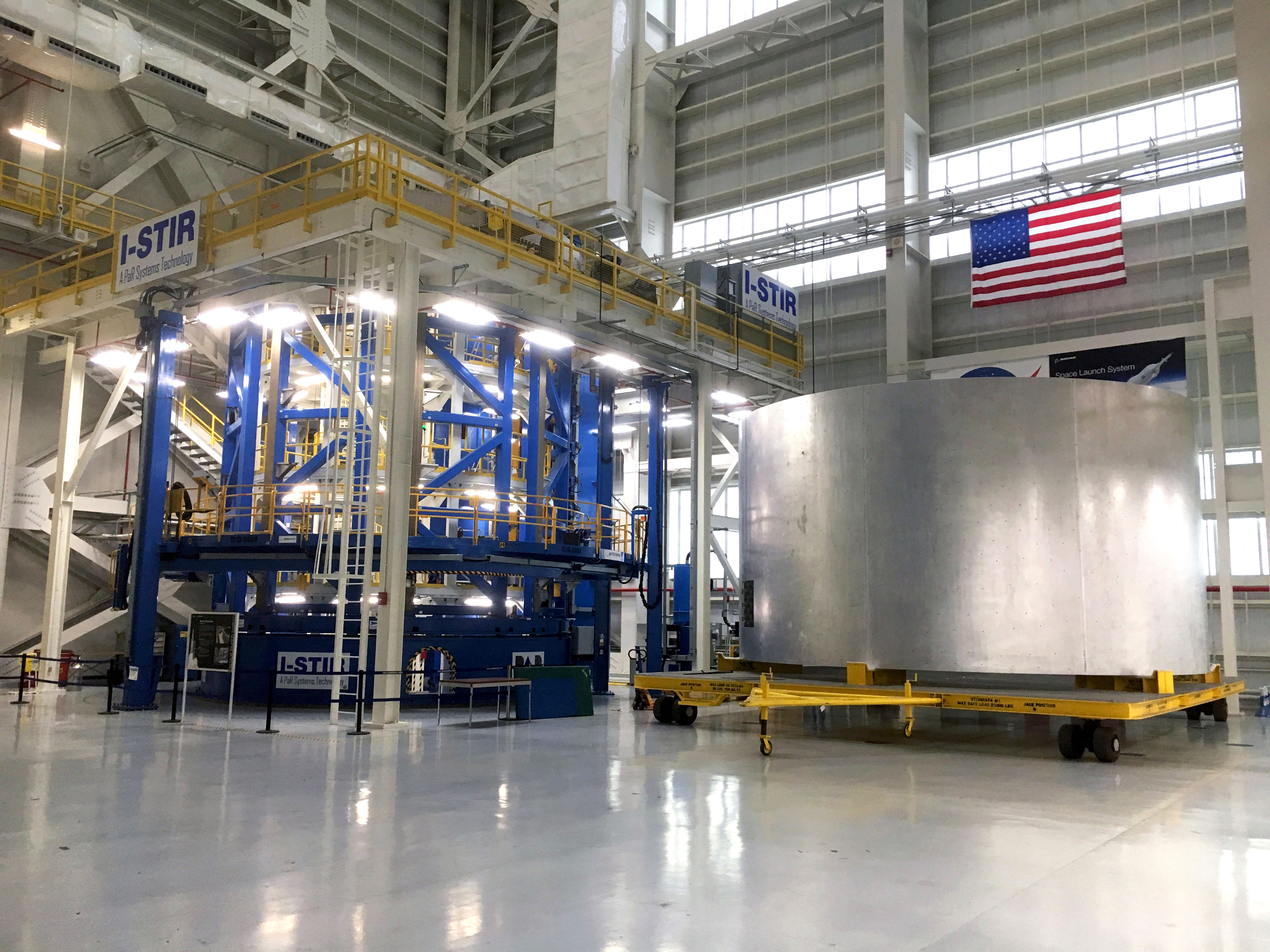 The Vertical Weld Center tool used to fabricate barrel segments for the SLS liquid hydrogen and oxygen core stage tanks via vertical friction stir welding operations at NASA’s Michoud Assembly Facility in New Orleans. To the right of the welder is the weld confidence barrell. Credit: Chase Clark