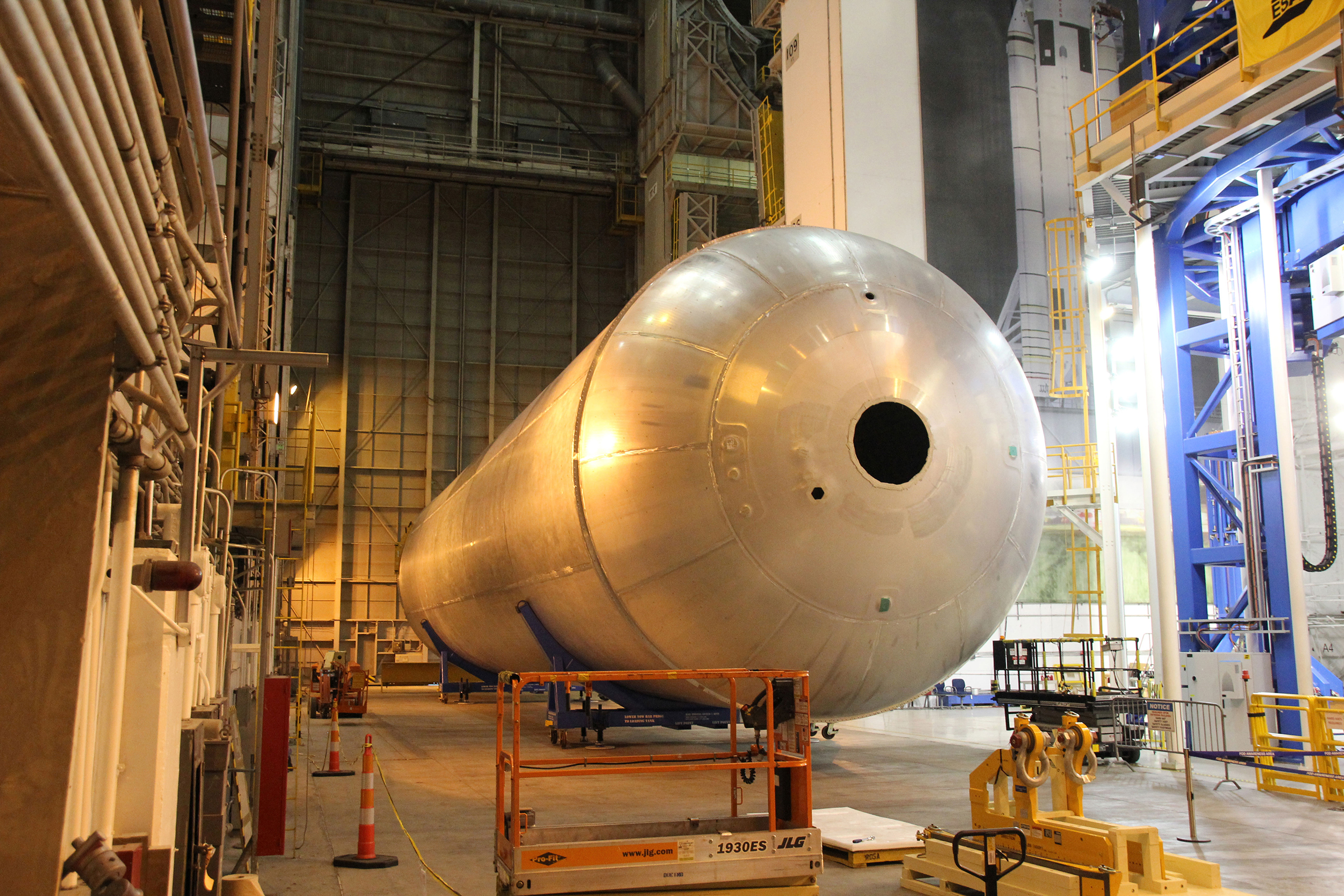 The newly assembled first liquid hydrogen tank, also called the qualification test article, for NASA’s new Space Launch System rocket lies horizontally beside the Vertical Assembly Center robotic weld machine (blue) on July 22, 2016. It was lifted out of the welder after final welding was completed at NASA’s Michoud Assembly Facility in New Orleans. Credit: Ken Kremer