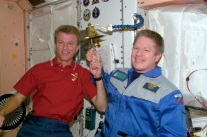 Astronauts Brent W. Jett, Jr. (left) and William M. Shepherd participate in an old Navy tradition of ringing a bell to announce the arrival or departure of someone to a ship.The bell is mounted on the wall in the Unity node of the International Space Station (ISS). Credit: NASA