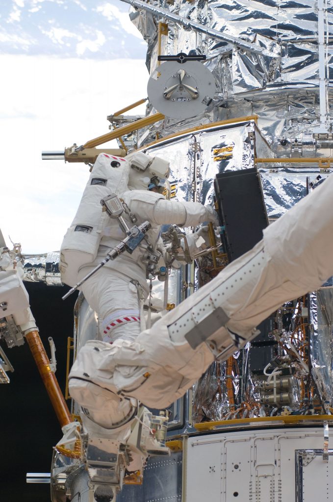 While standing on the end of Atlantis’ RMS arm, STS-125 mission specialist Michael Good works on the Hubble Space Telescope. Good and fellow mission specialist Mike Massimino (out of frame) continue work on the HST, locked down in the orbiter’s cargo bay. Credit: NASA